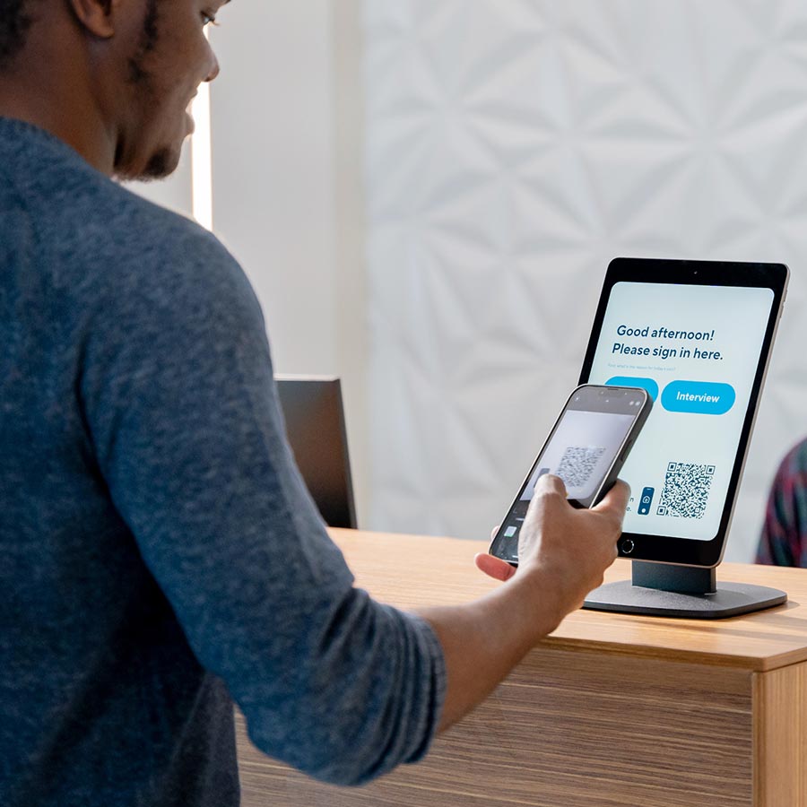 Person scanning a smartphone QR code at a reception tablet